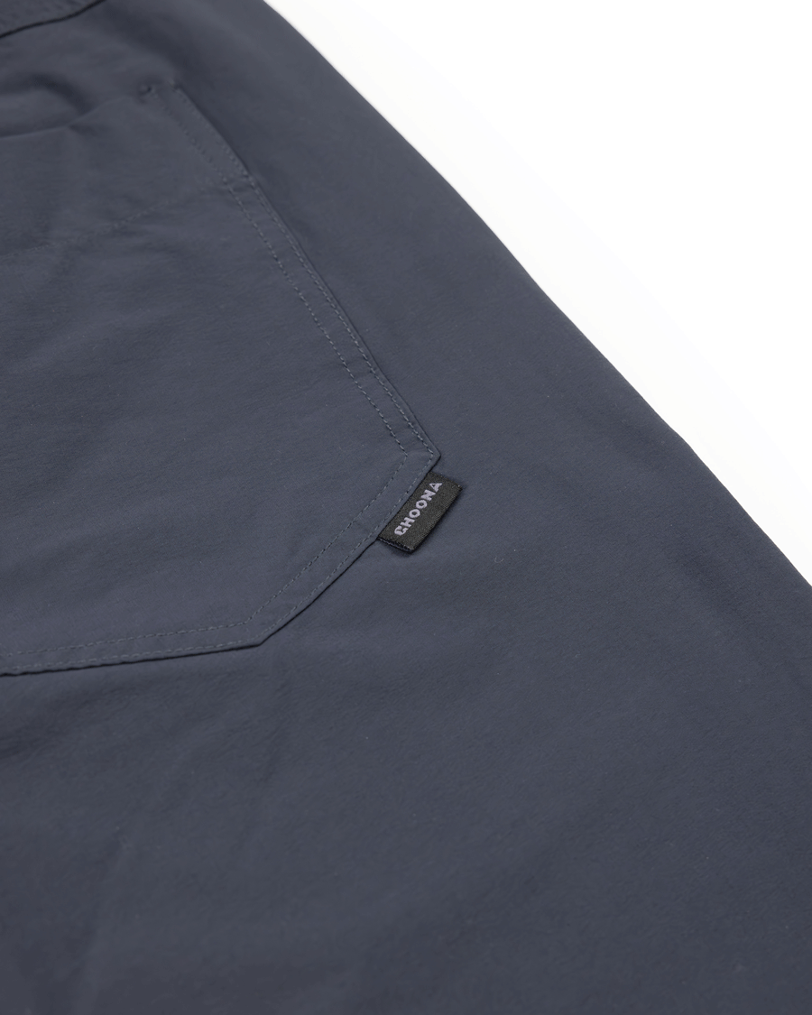 Close-up of the Choona Drifter Pant’s dark blue four-way stretch fabric, showing a stitched pocket and small black SHOWA tag on the side, set against a white background.