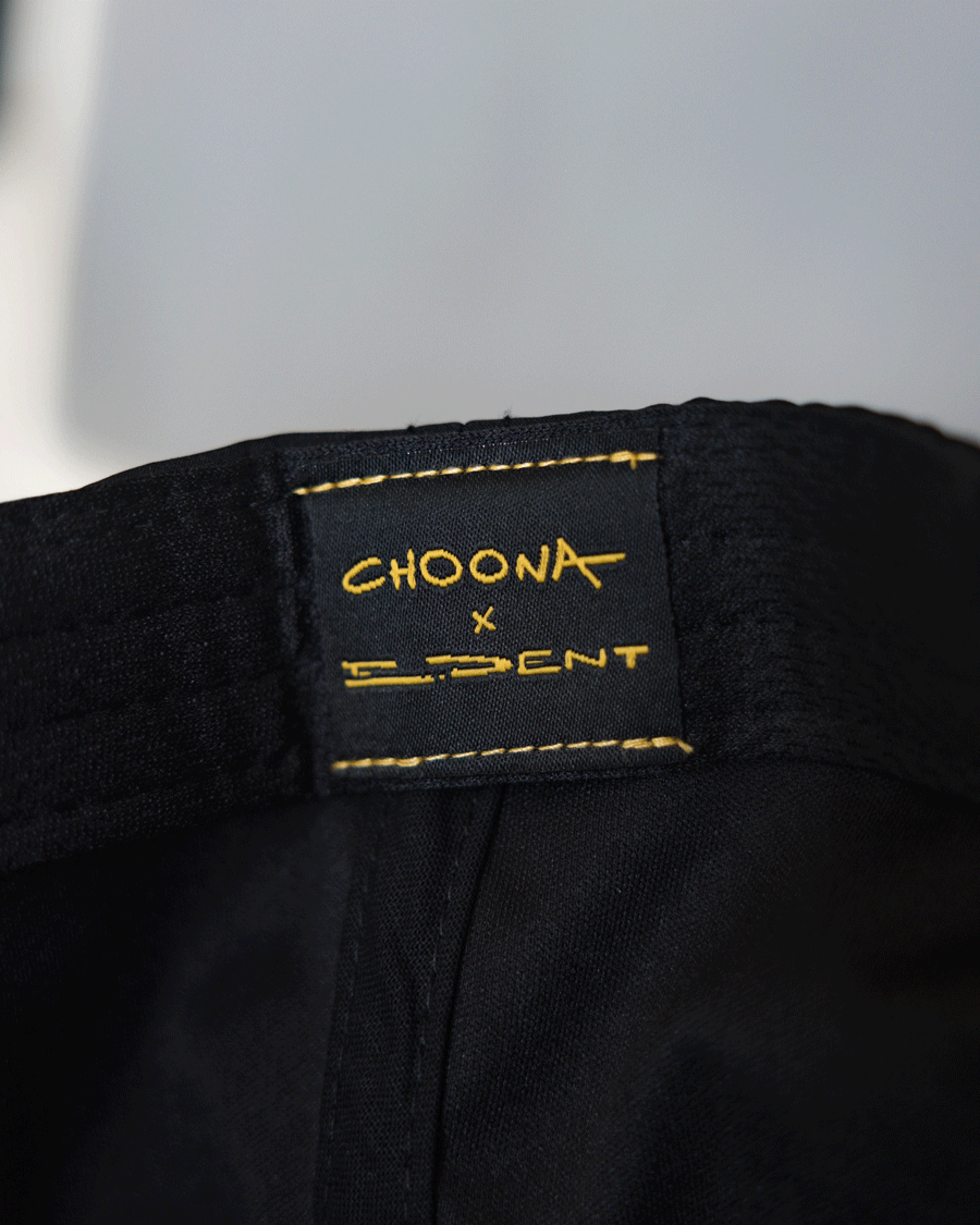 Close-up of a black fabric label with yellow stitching reading CHOONA x D.DENT, sewn onto the Choona X Dent Redfish Snapback by Choona.