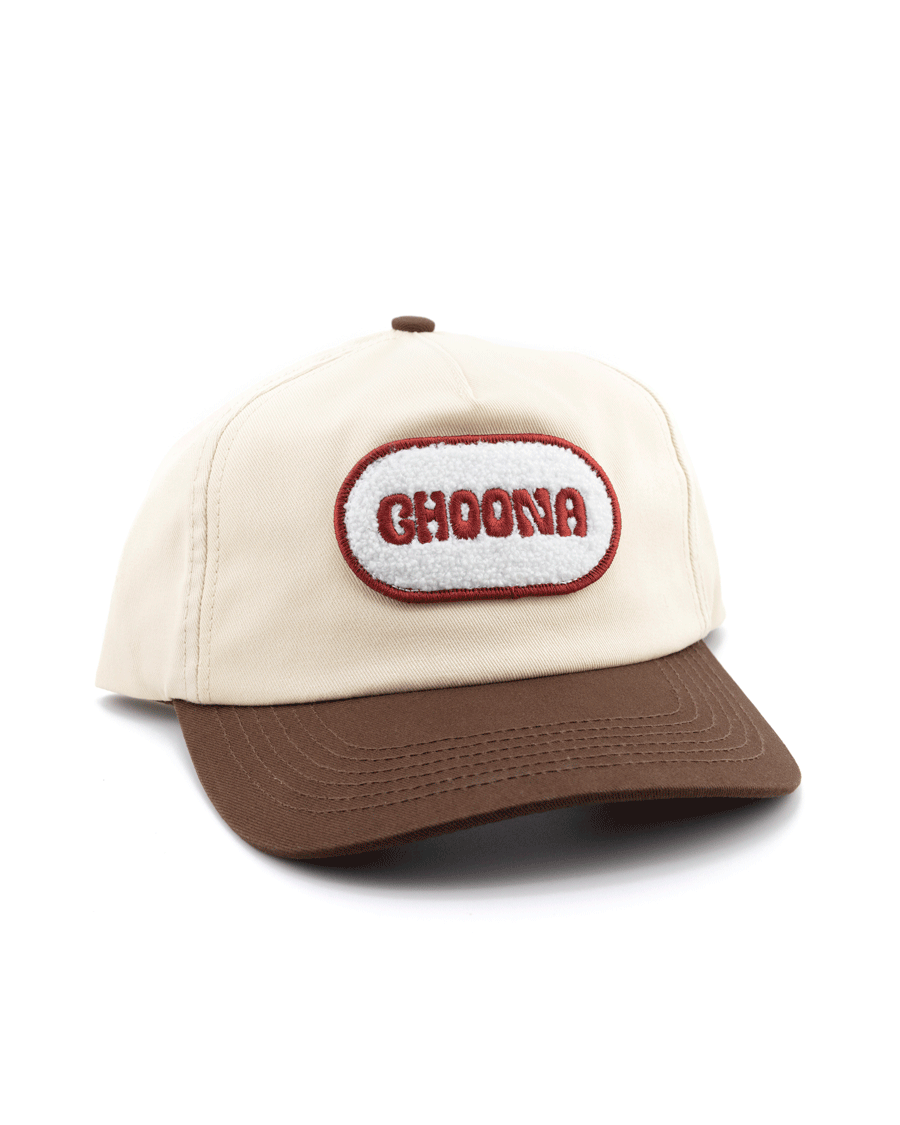 The Choona Fly Patch Snapback is a beige unstructured cotton twill cap with a brown brim, white oval fly patch outlined in red, and bold red CHOONA embroidery.