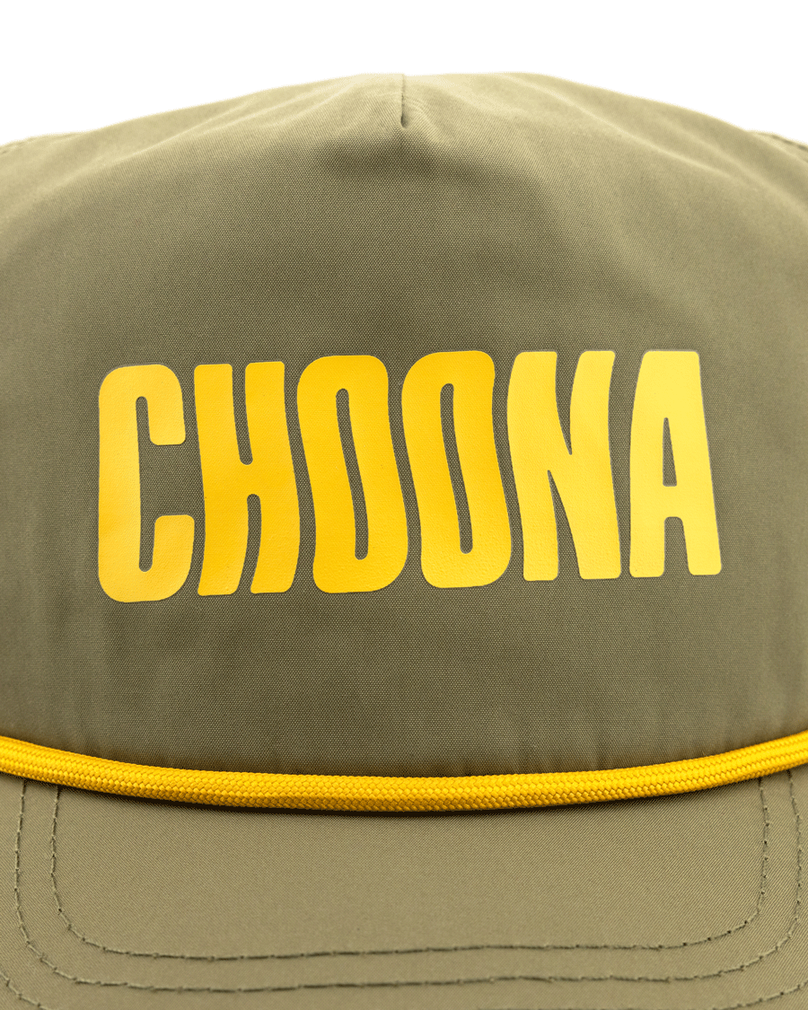 A close-up of the Choona Wavy Snapback in olive green, featuring bold yellow CHOONA lettering on the front and crafted with quick-drying fabric for coastal adventures.