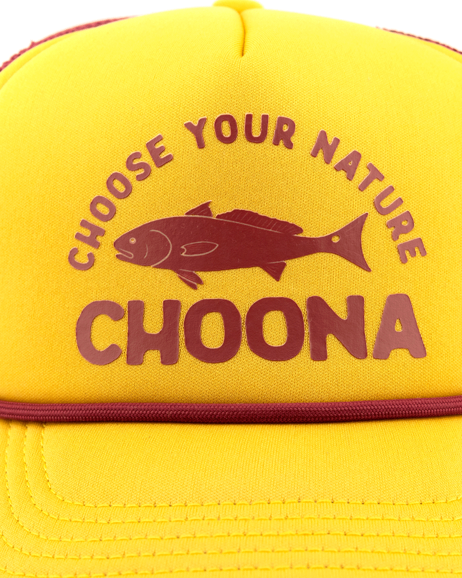 The Choona Redfish Foam Snapback is a yellow cap with maroon CHOOSE YOUR NATURE CHOONA text and a fish illustration between the lines, offering throwback style and a modern fit.