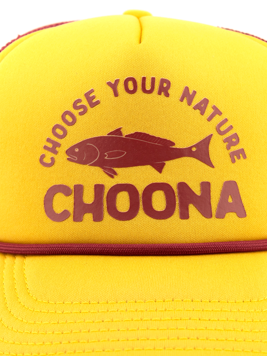 The Choona Redfish Foam Snapback is a yellow cap with maroon CHOOSE YOUR NATURE CHOONA text and a fish illustration between the lines, offering throwback style and a modern fit.