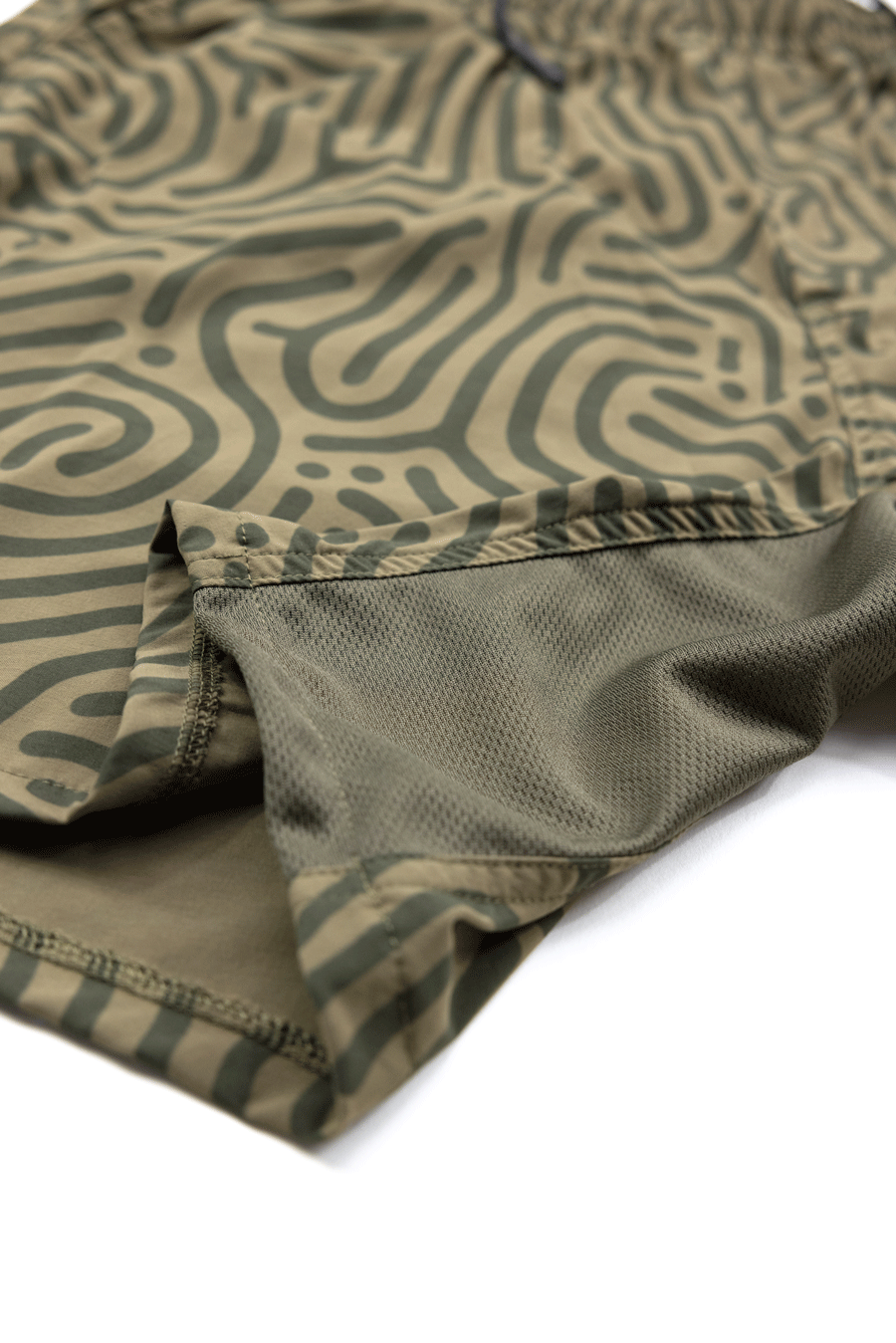 Close-up of Choona Shore Short in green and black pattern, featuring a side slit, visible mesh lining, and moisture-wicking tech—perfect for coastal activities.