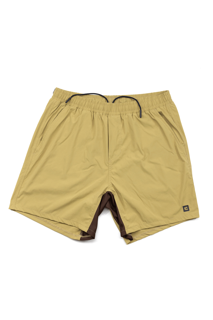 The Choona Shore Short features tan athletic styling, moisture-wicking fabric, an elastic waistband with black drawstring, side pockets, a logo patch, and visible brown lining at the leg openings—ideal for coastal activities.