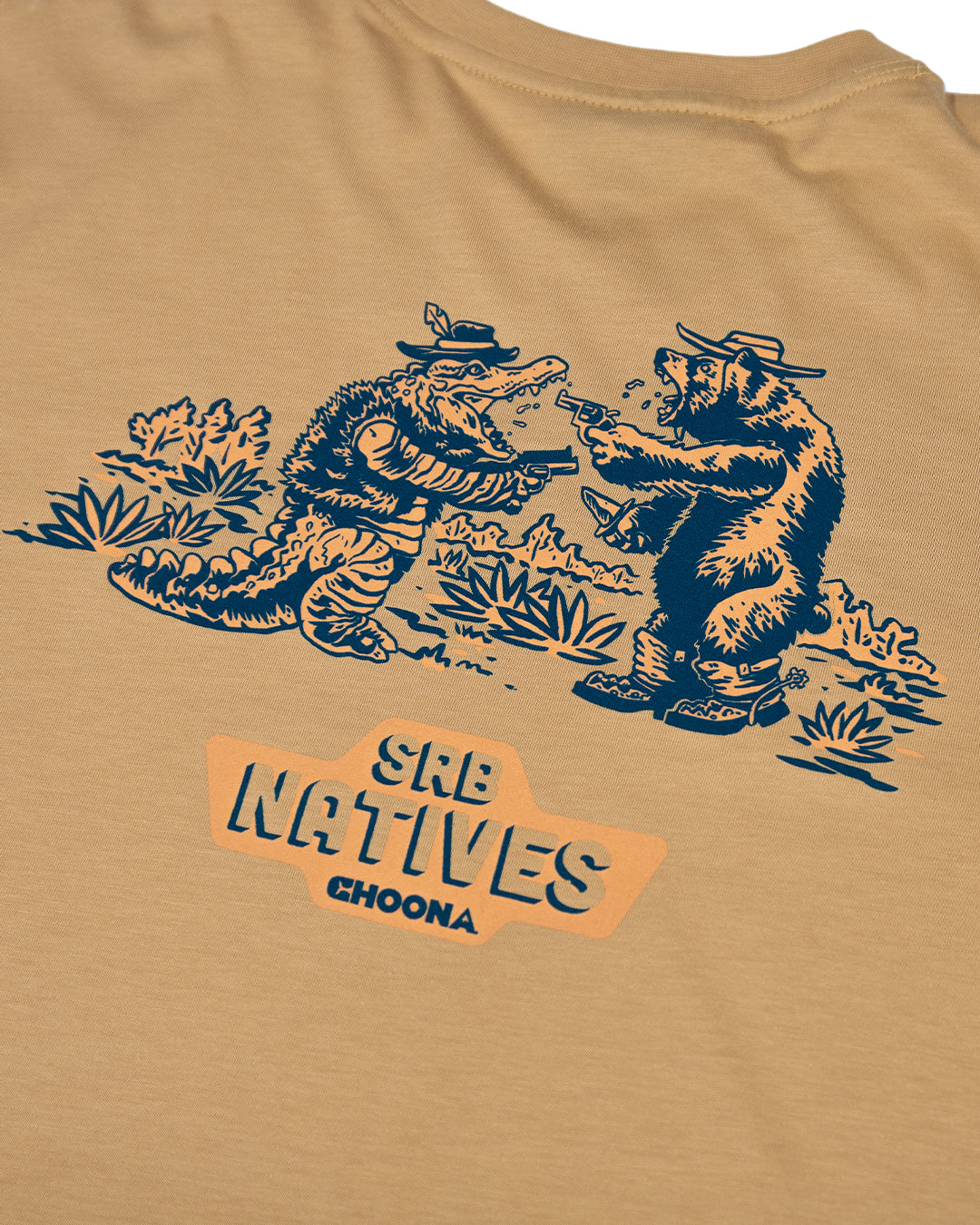 The SRB Natives Graphic Tee by Choona features an illustration of a hat-wearing alligator and bear holding weapons, with “SRB NATIVES CHOONA” text—delivering laidback Santa Rosa Beach style on tan Pima cotton.