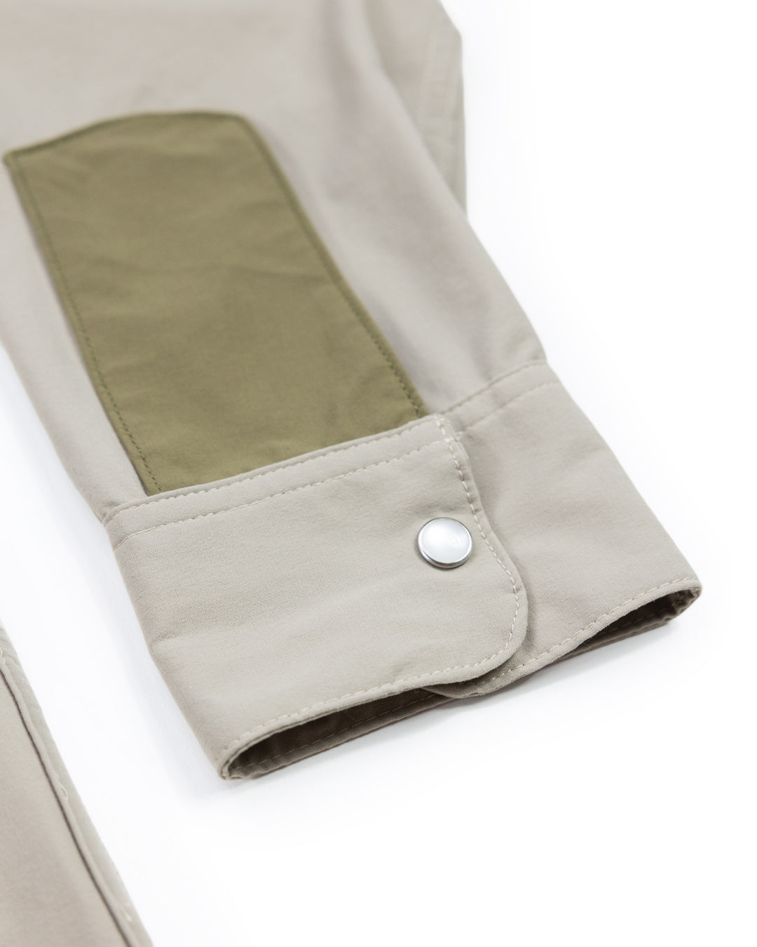 A close-up of the Choona Panhandle Pearl Snap shirt in beige, showing an olive green rectangular patch and a silver snap cuff button, laid flat on white—embodying classic coastal cowboy style from Florida’s Panhandle.