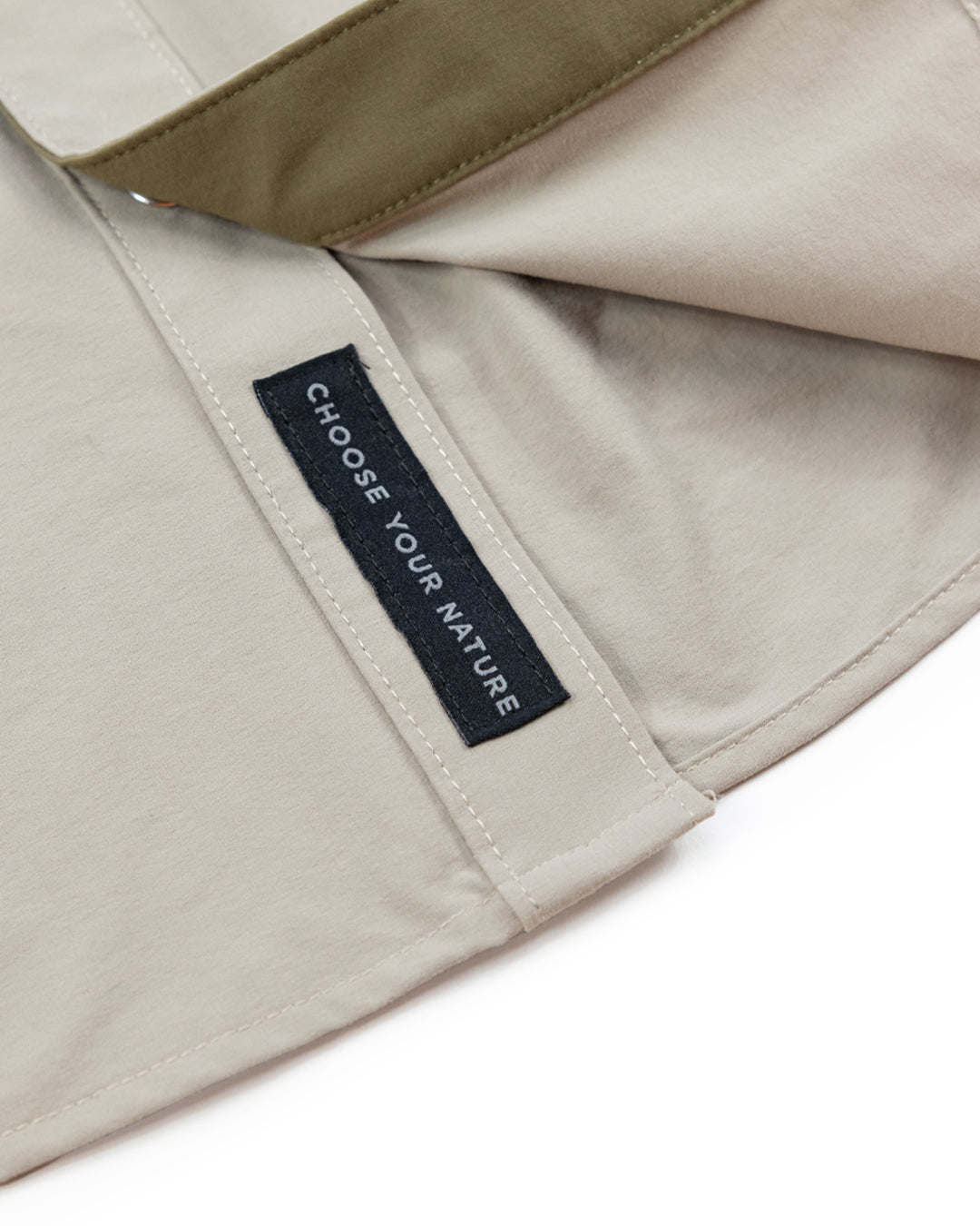 A close-up of the beige Panhandle Pearl Snap by Choona, featuring a black CHOOSE YOUR NATURE label and a khaki green strap—ideal for your next coastal cowboy adventure in the Florida Panhandle.