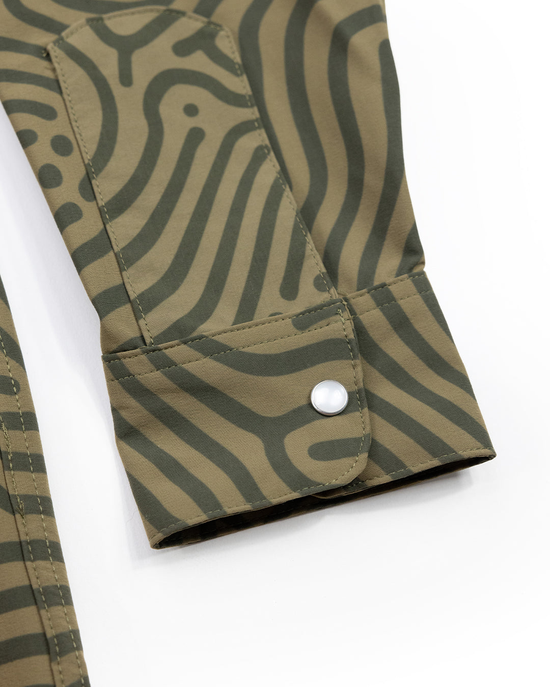 Close-up of a green Choona Panhandle Pearl Snap shirt sleeve with lighter green wavy stripes and a single white snap button on the cuff, inspired by coastal cowboy style from the Florida Panhandle.