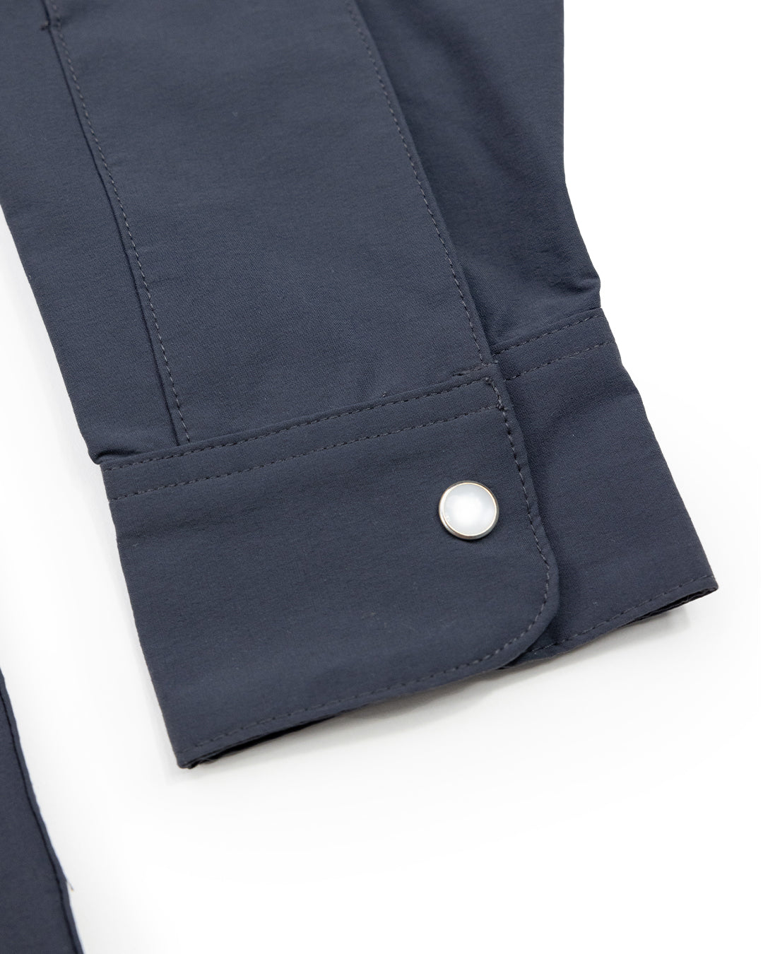 A close-up of a dark blue Choona Panhandle Pearl Snap cuff with a silver button and detailed stitching on white—ideal for adding coastal cowboy flair to your Florida Panhandle wardrobe.