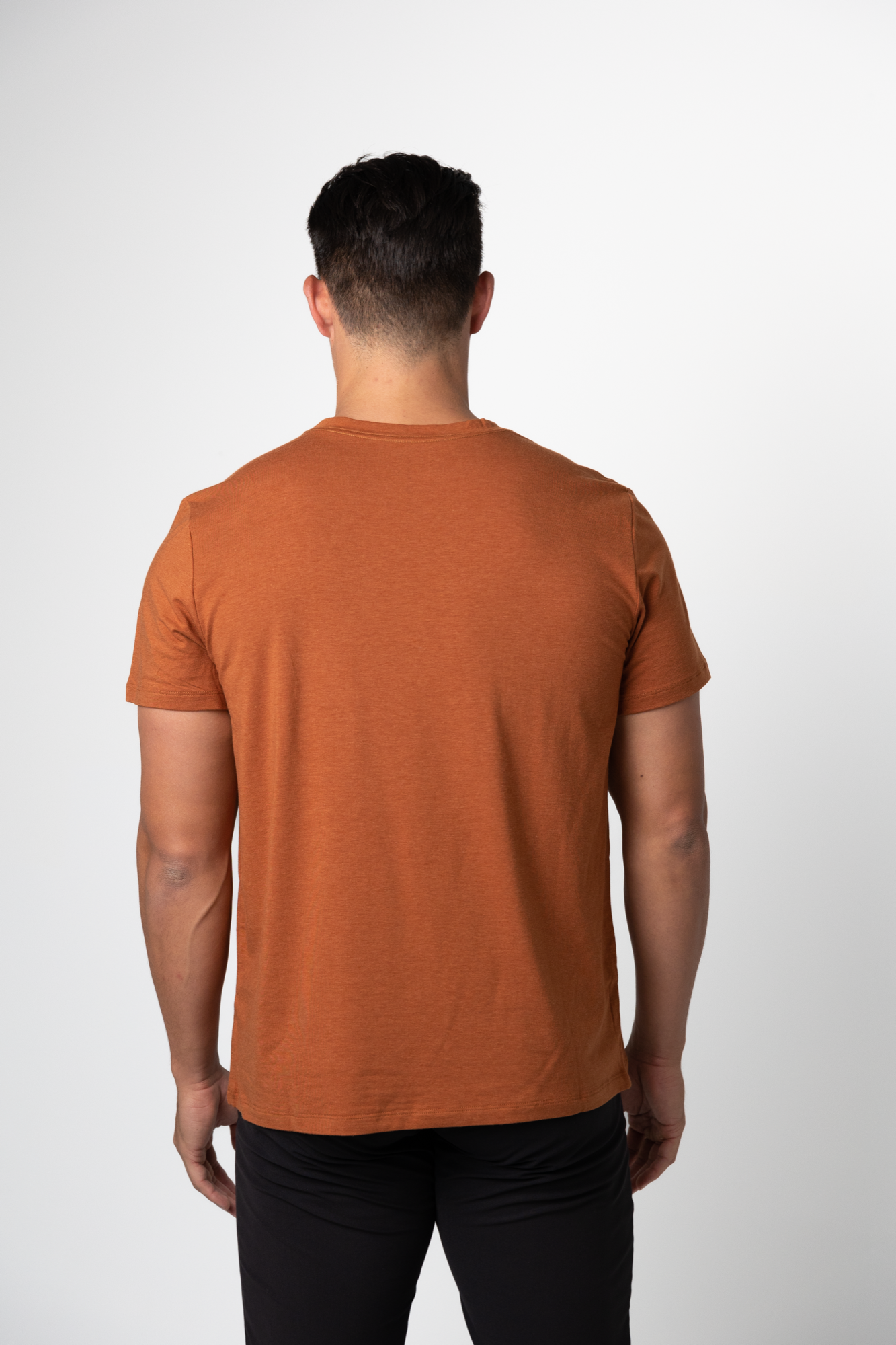 A man with short dark hair wears a Choona Panhandle Pocket Tee made from a sustainable Lyocell blend and black pants, standing with his back to the camera against a plain white background.