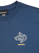 The Stay Awhile Graphic Tee by Choona features a blue color, white stylized fish, yellow CHOONA text, 100% Pima cotton fabric, and a black branded collar tag—ideal for your outdoor lifestyle.