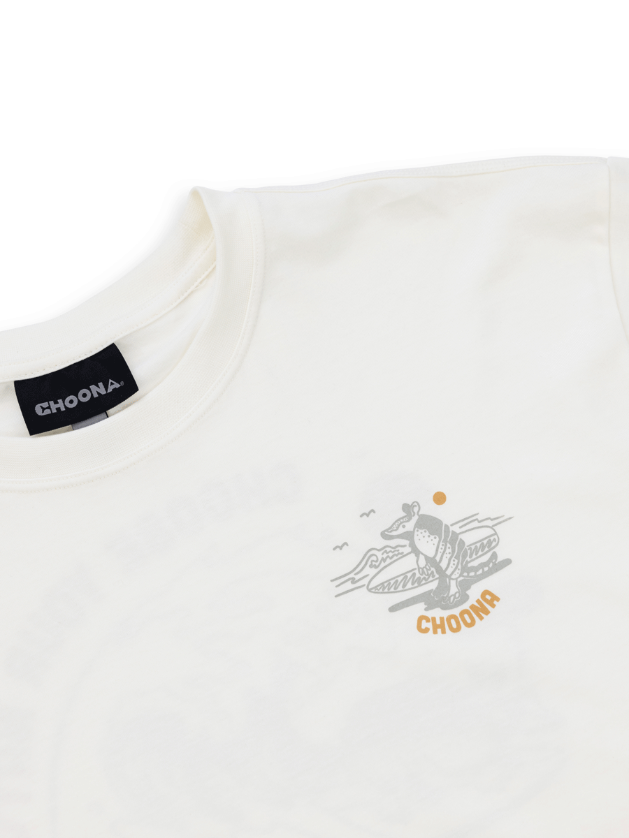 The Choona Armachillo Graphic Tee is a white, 100% Pima cotton shirt with a small pelican, waves, and sun graphic plus CHOONA on the chest; features a black CHOONA label inside the collar.