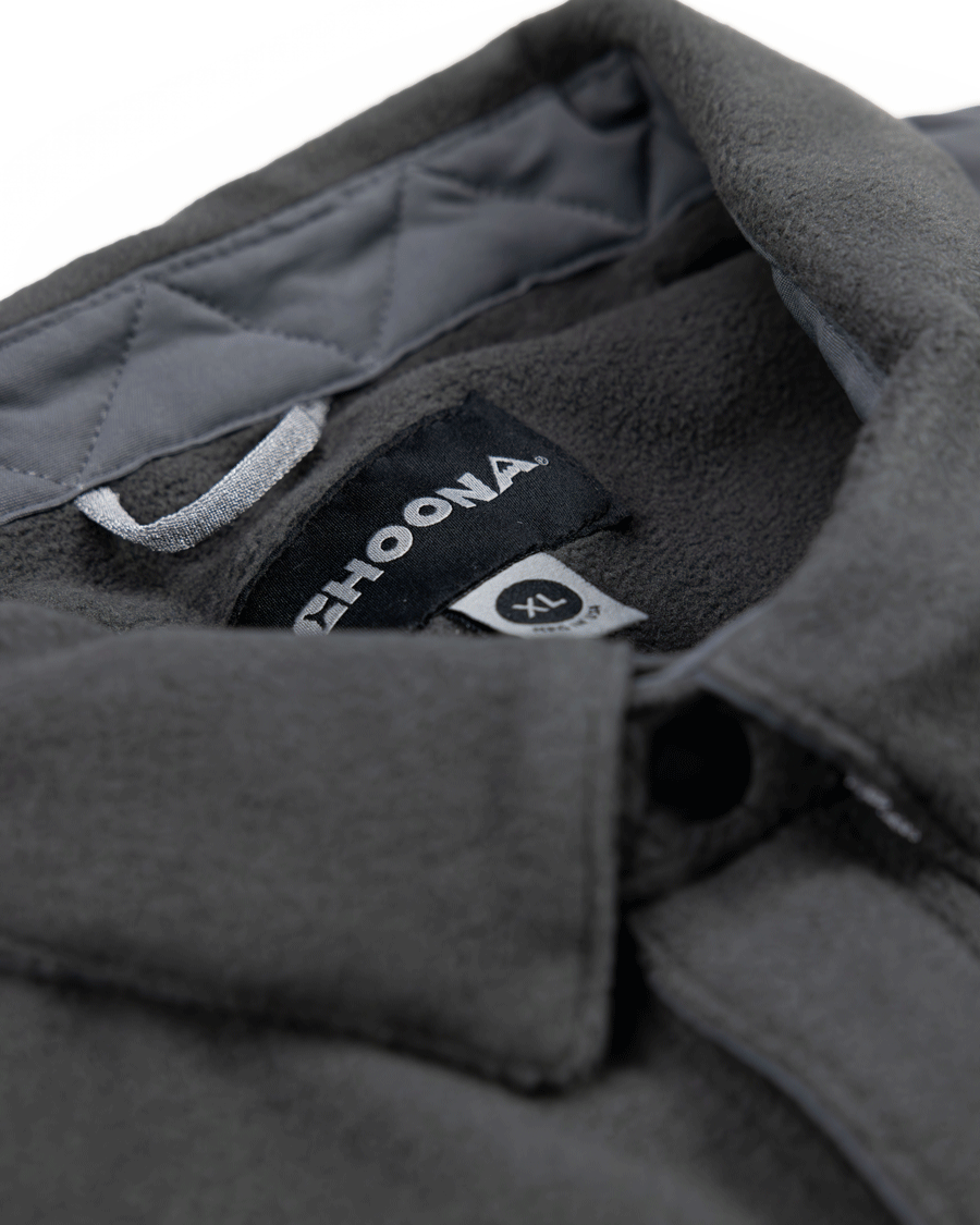 Close-up of the dark gray Skipper Shacket by Choona in size XL, showing its collar and tags against a quilted inner lining. Made from recycled polyester, its ideal for layering in cold weather.