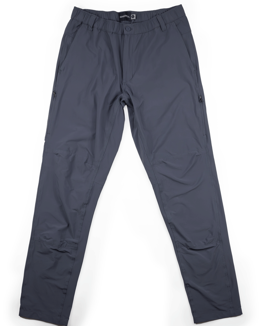 The Choona Drifter Pant in dark gray is lightweight, features full-length four-way stretch fabric, zippered side pockets, and an elastic waistband, shown laid flat on a white background.