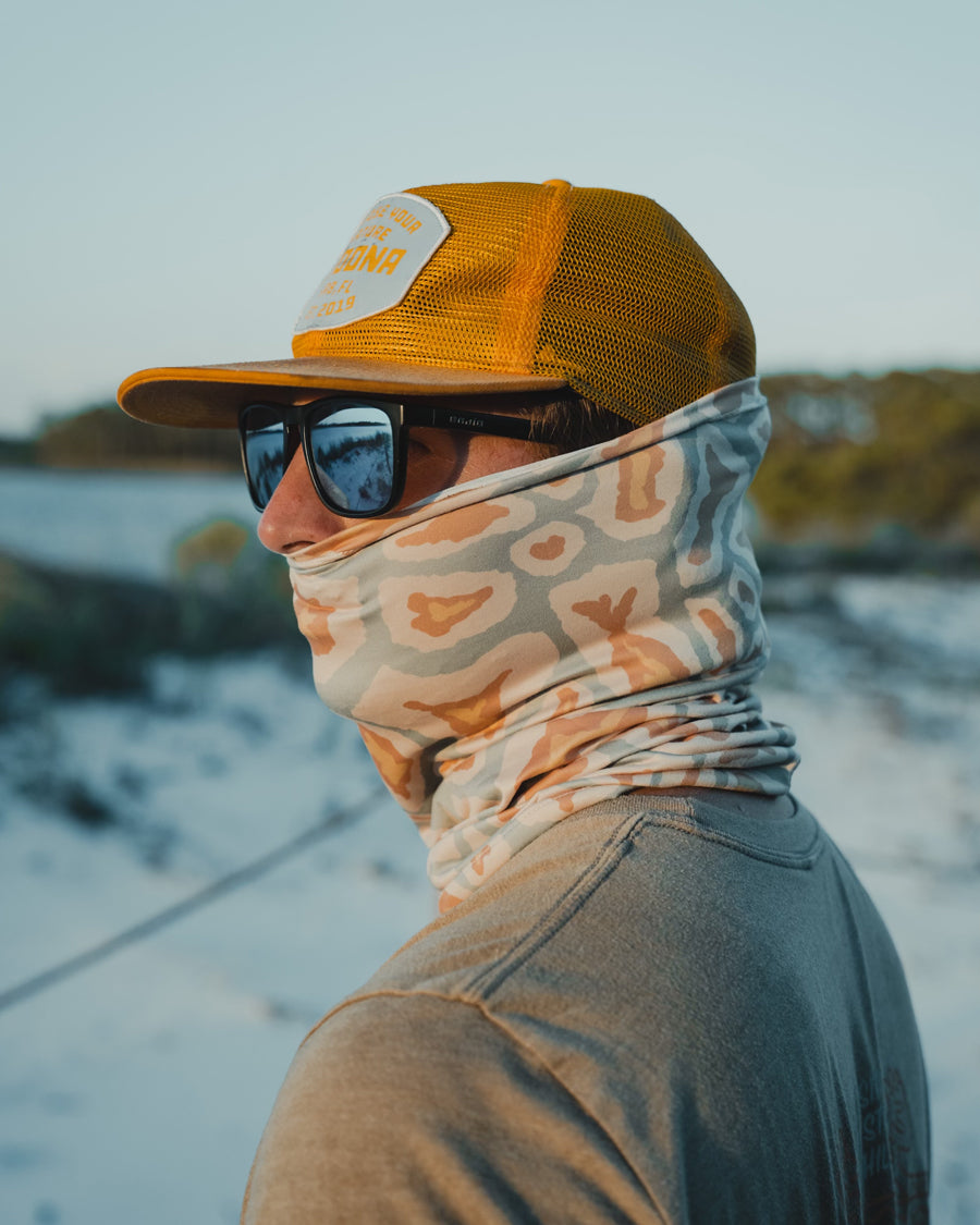 A person wearing a yellow cap, dark sunglasses, and a Choona Grayton Sun Mask stands outdoors with a blurred natural background and soft lighting, highlighting effective outdoor protection.