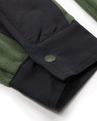Close-up of the Choona Skipper Shacket sleeve in dark green and black recycled polyester, featuring a green snap button on the cuff that highlights the contrasting fabric textures.