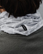Close-up of a person wearing the Choona Grayton Sun Mask, an ultra lightweight grey neck gaiter with a geometric pattern and visible black CHOONA tag, paired with a dark grey shirt for outdoor protection.