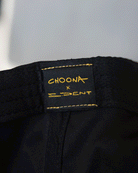 Close-up of a black fabric label with yellow stitching reading CHOONA x D.DENT, sewn onto the Choona X Dent Redfish Snapback by Choona.
