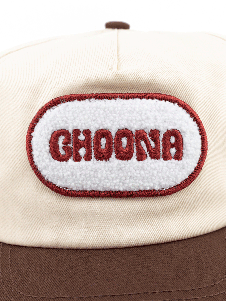 The Choona Fly Patch Snapback is a cream cotton twill cap with a brown brim, featuring a white oval patch outlined in red and embroidered with CHOONA in bold red letters.