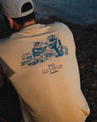 A person wearing the Choona SRB Natives Graphic Tee in beige, featuring two cartoon crocodiles facing each other and SRB NATIVES CHOONA printed below the graphic on the back.