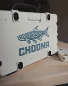 A white hard plastic case with black latches displays a blue tarpon decal and the bold Choona name, plus a subtle brand logo below—complete with an adventure-inspired sticker that encourages you to Choose Your Nature.