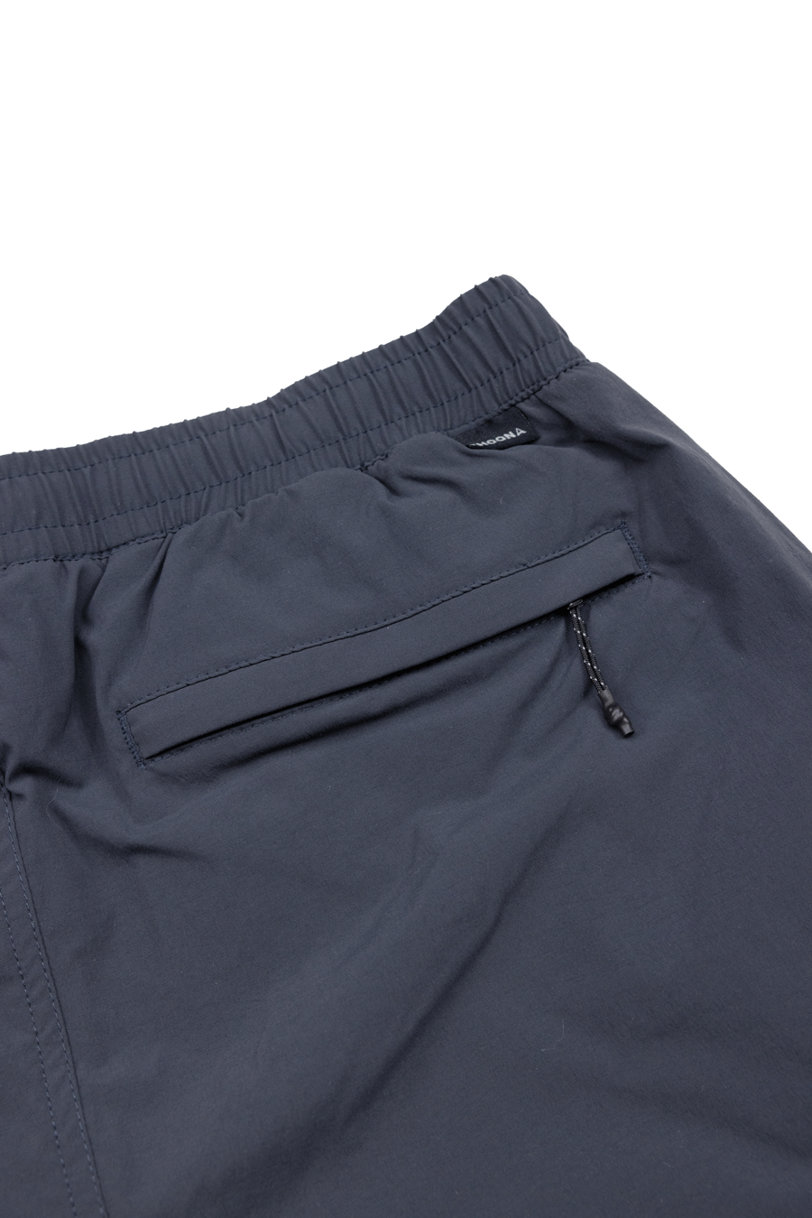 Close-up of the Choona Shore Short in navy blue, showing the elastic waistband, zippered pocket with pull tab, and wicking tech—perfect for coastal adventures.