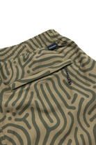 Close-up of Choona Shore Short—green shorts with an abstract wavy line pattern, elastic waistband, zipper pocket, and a small black SINOBIA tag. Perfect for coastal activities with built-in wicking technology.