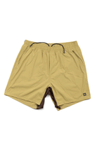 The Choona Shore Short features tan athletic styling, moisture-wicking fabric, an elastic waistband with black drawstring, side pockets, a logo patch, and visible brown lining at the leg openings—ideal for coastal activities.