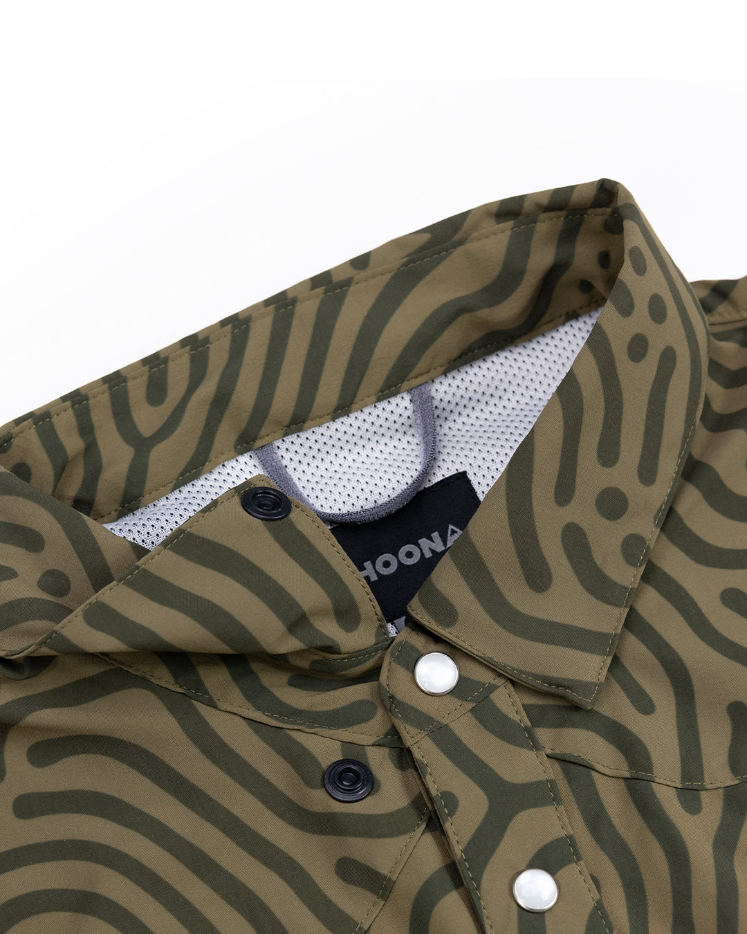 Close-up of the Choona Panhandle Pearl Snap in green, showcasing a wavy dark green pattern, contrasting white and black snap buttons, and a black collar tag with white text—capturing coastal cowboy style.