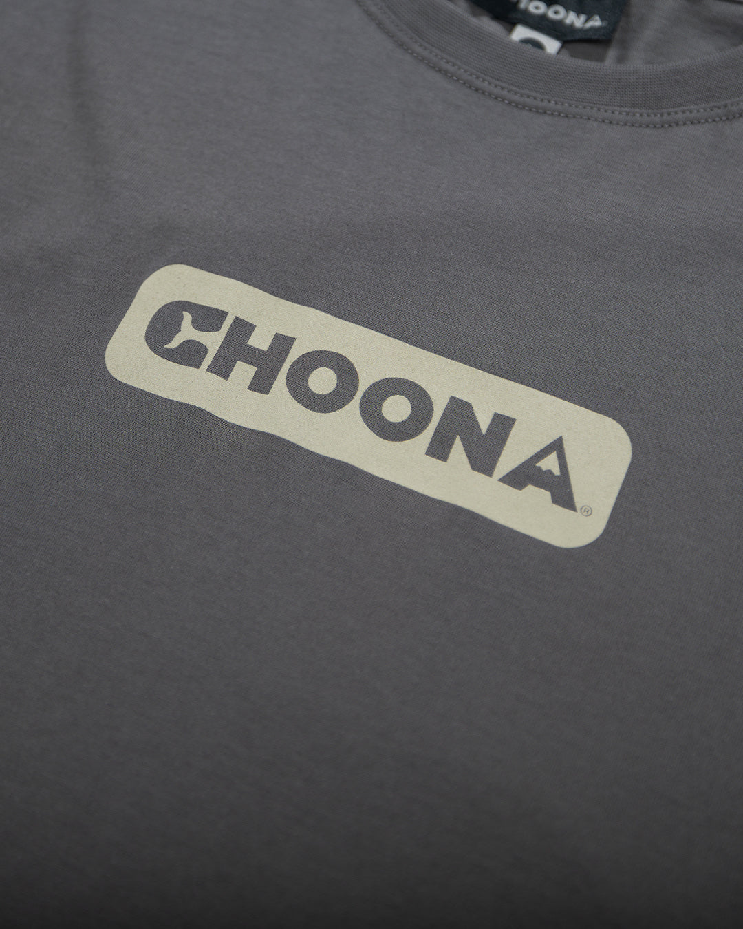 The Choona Logo Graphic Tee by Choona is a dark gray shirt made from USA-grown cotton, featuring bold, light-colored "CHOONA" lettering inside a rectangle on the chest.