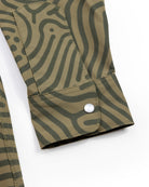 Close-up of a green Choona Panhandle Pearl Snap shirt sleeve with lighter green wavy stripes and a single white snap button on the cuff, inspired by coastal cowboy style from the Florida Panhandle.