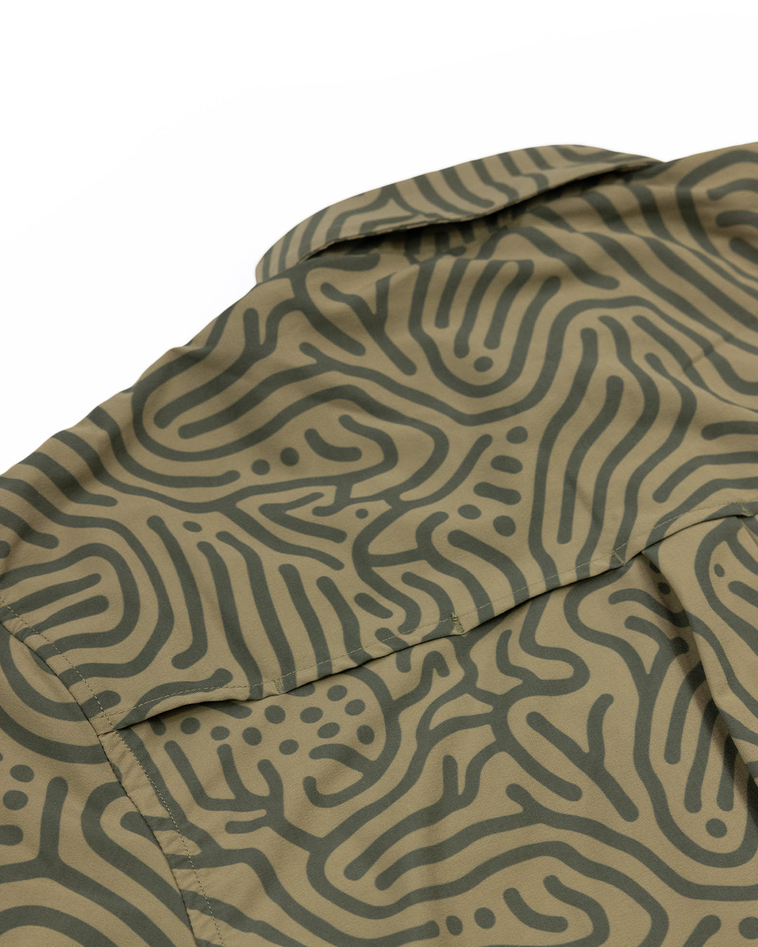 Close-up of the Choona Panhandle Pearl Snap shirt in green, featuring an abstract wavy dark green pattern and a collar. The coastal cowboy style shirt is laid flat on a white background.