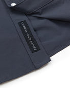 A close-up of the Panhandle Pearl Snap by Choona shows dark blue fabric and a black label with CHOOSE YOUR NATURE in white. This shirt captures a coastal cowboy vibe, ideal for the Florida Panhandle.