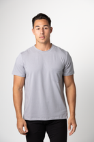 A young man with short dark hair wears a Choona Panhandle Pocket Tee in a light gray Lyocell blend and black pants, standing against a white background and looking at the camera with a neutral expression.