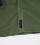 Close-up of Choona’s green Skipper Shacket in recycled polyester, with a black Choona tag and a snap button on the seam, set against a white background.